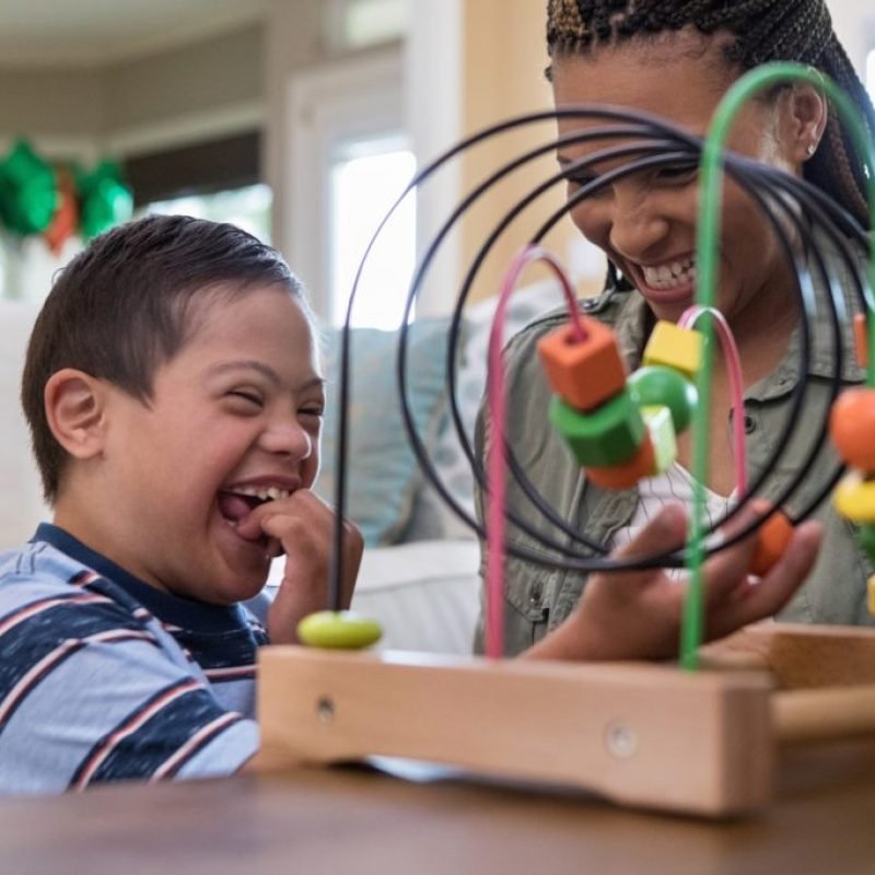 When the mid adult mom and her special needs son play in the living room, they laugh together.